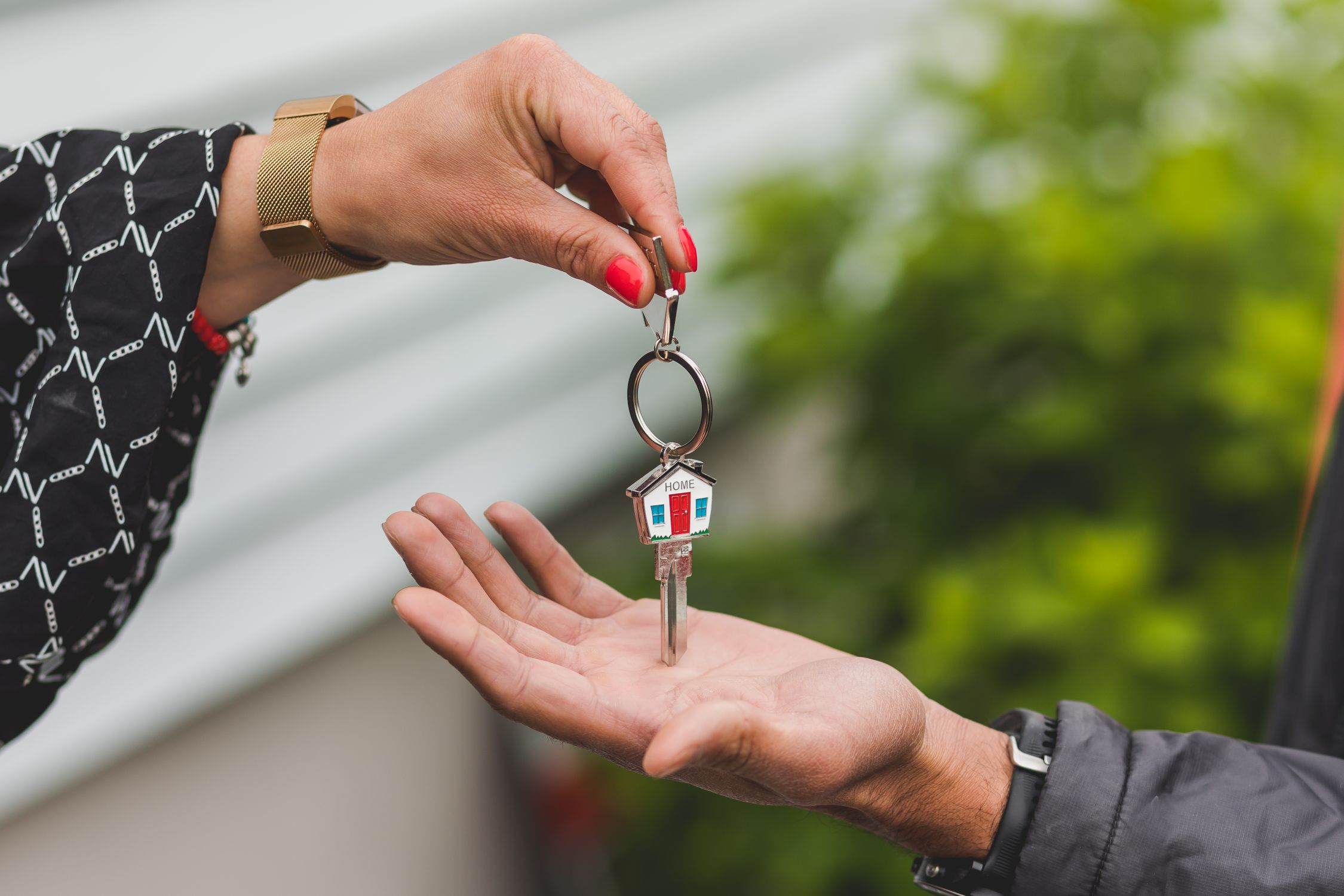A person handing house keys to another person’s open hand